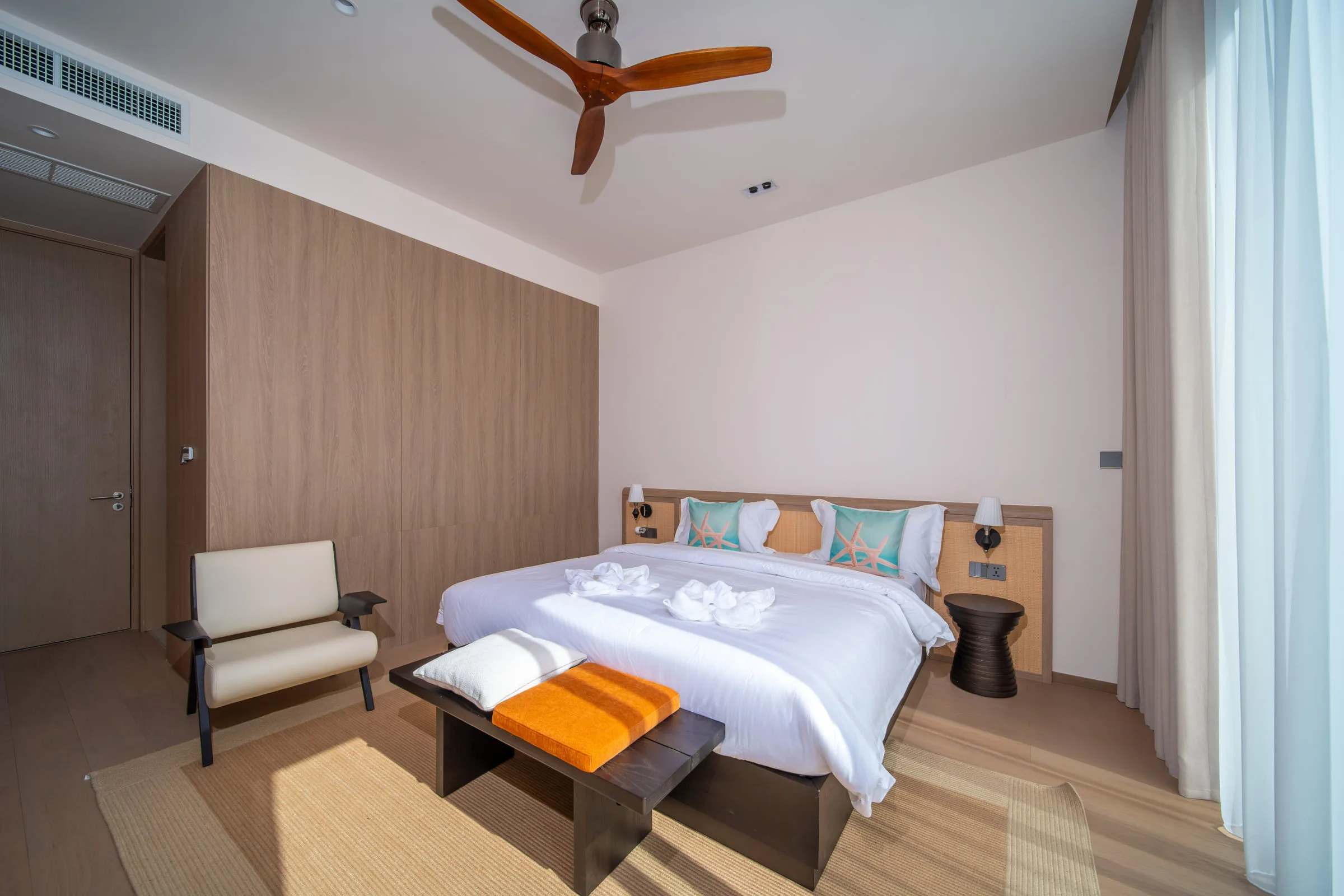 Bedroom with a full-height timber wardrobe wall, a double bed and a lounge chair