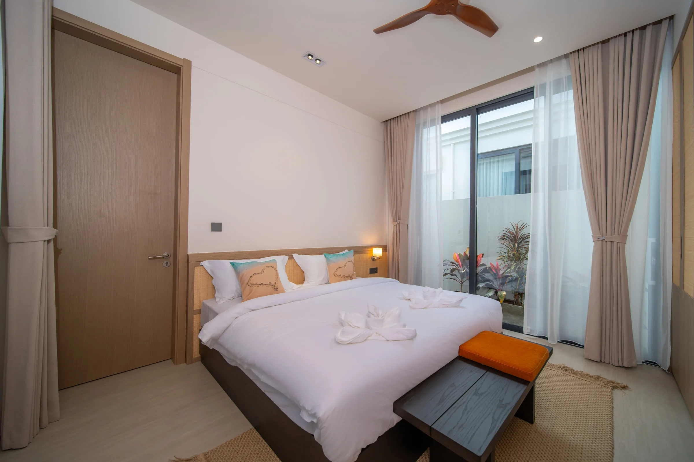 Bedroom with floor-to-ceiling curtains, a double bed and a bench at the foot of the bed