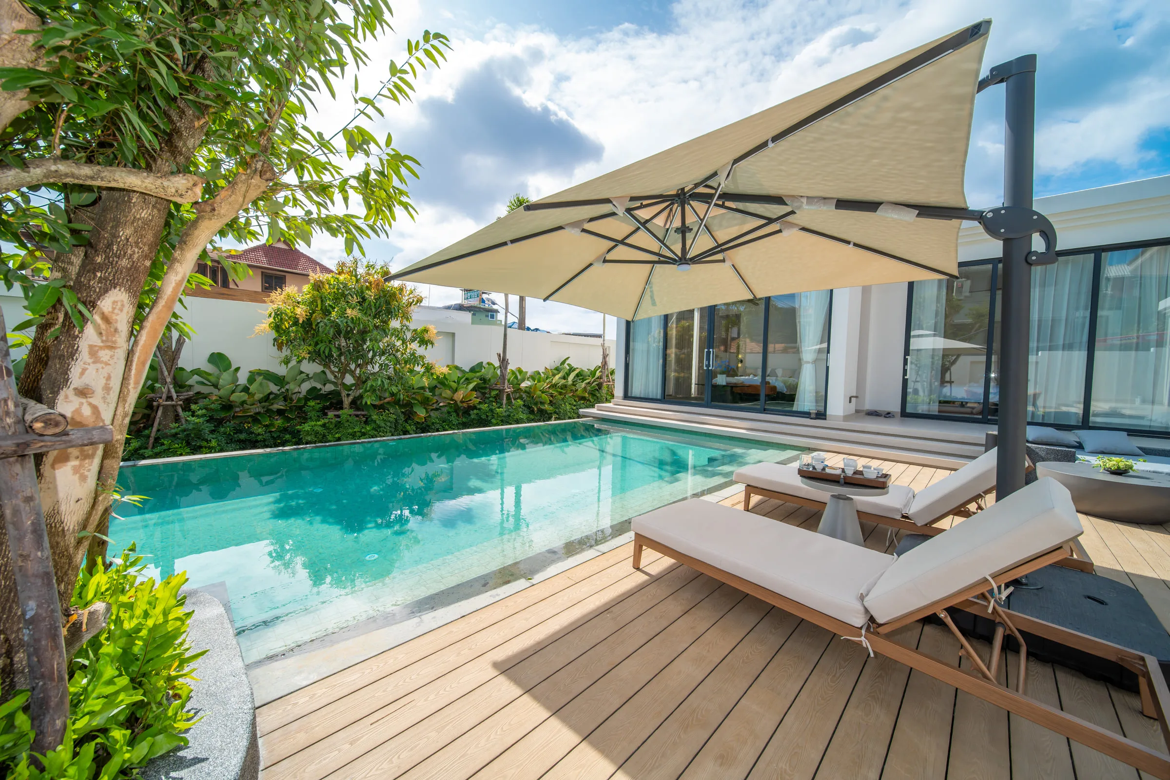 Swimming pool with two sun loungers and a cantilever parasol on the timber deck