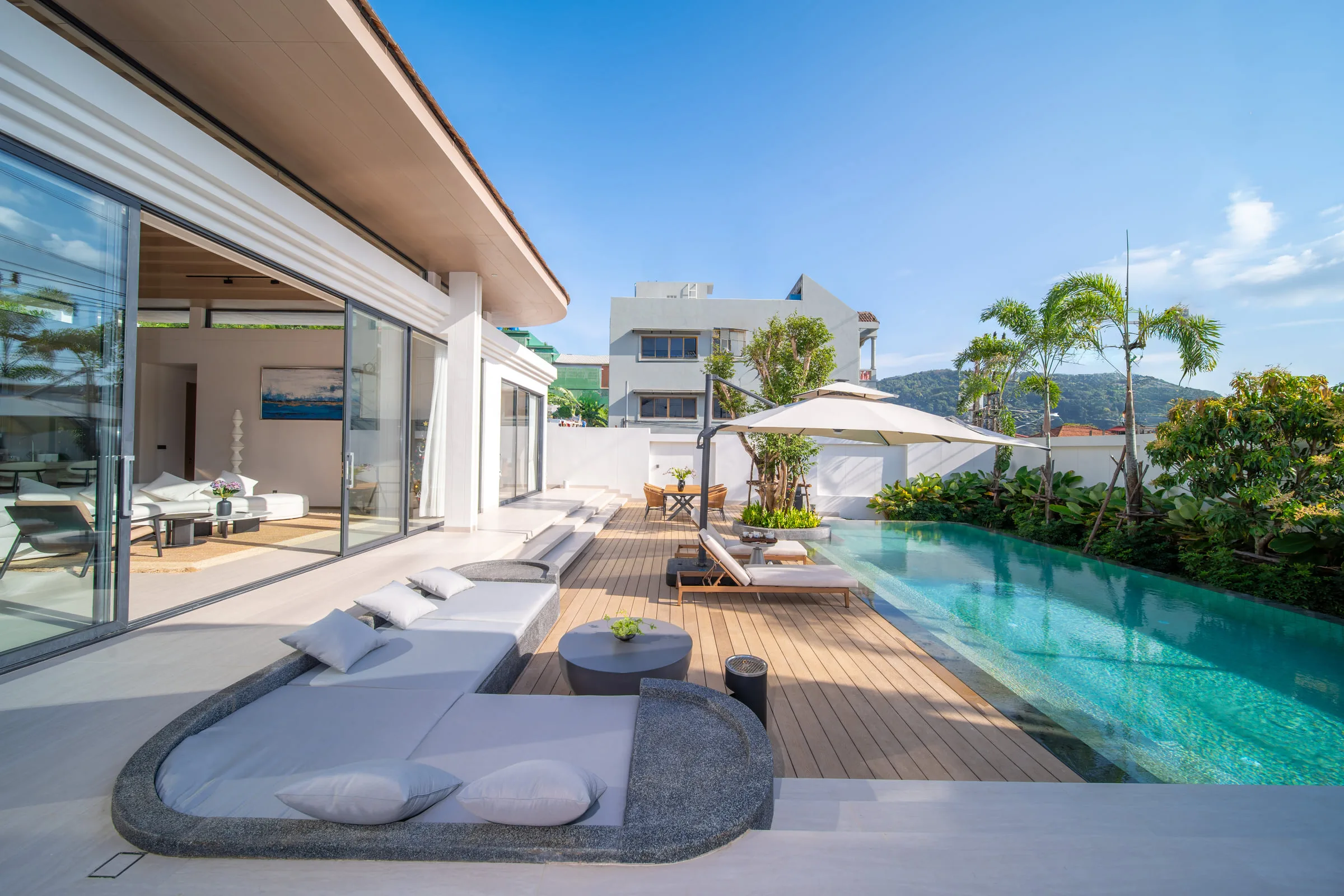 Pool terrace with sun loungers and a round daybed, the hillside visible beyond the boundary wall