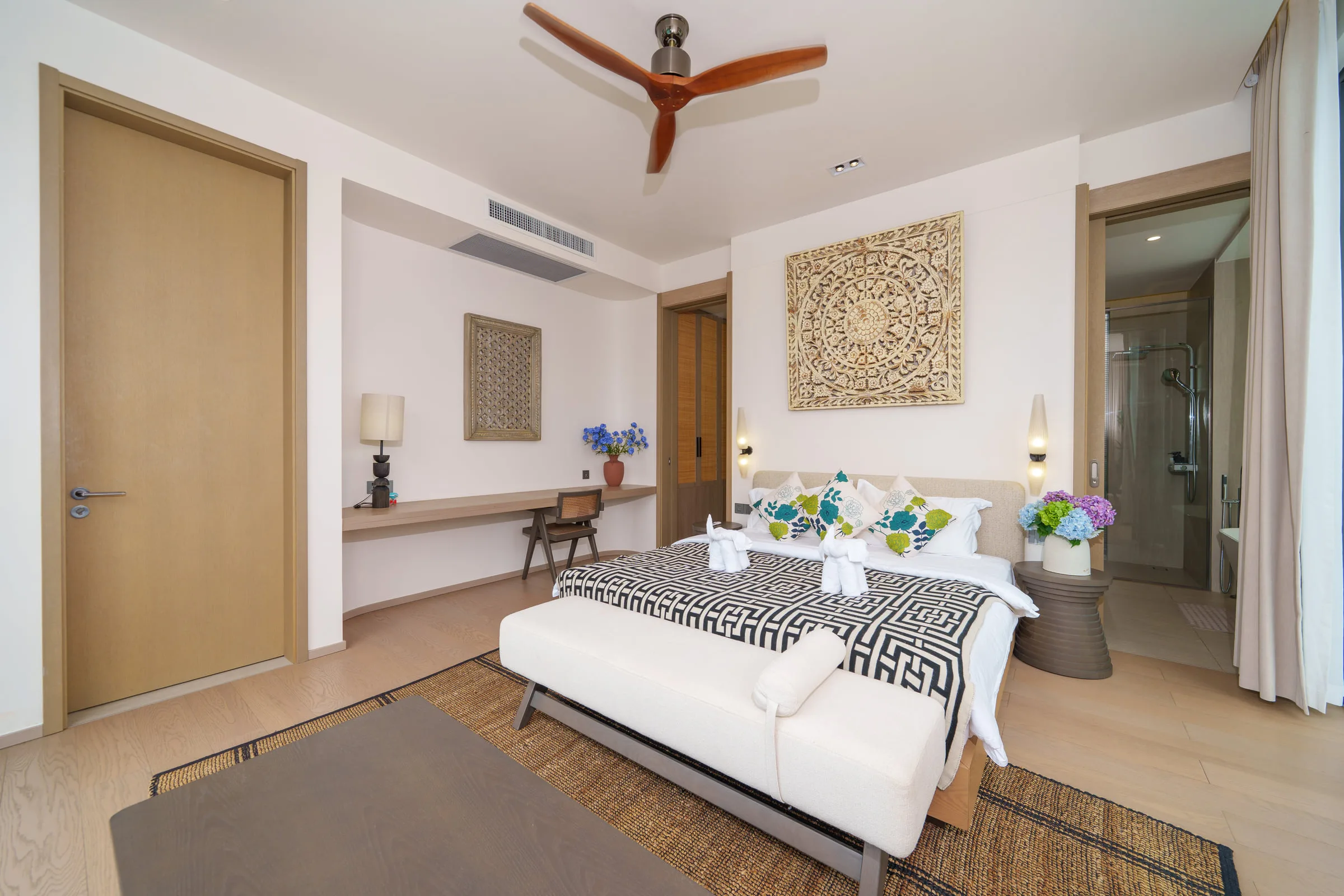 Bedroom with a double bed, a carved wall panel above the headboard and a bench at the foot