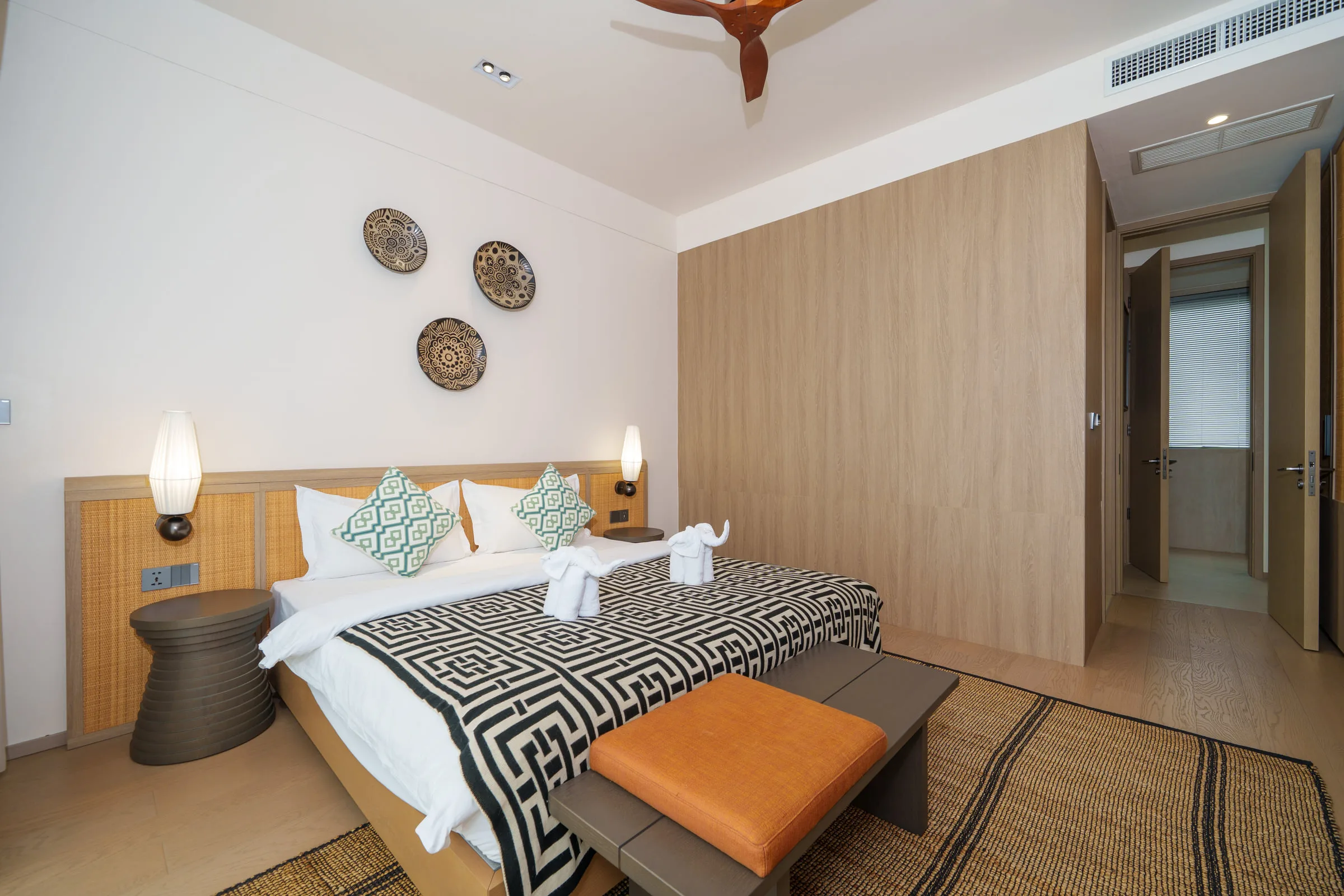 Bedroom with a timber feature wall, wall-mounted television and woven wall discs