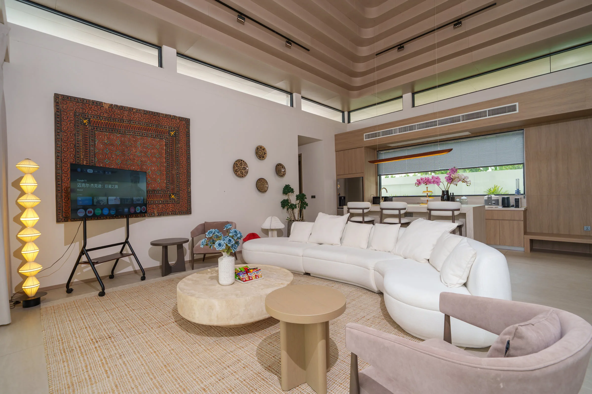 Living room with a curved sofa, armchairs and a high slatted timber ceiling