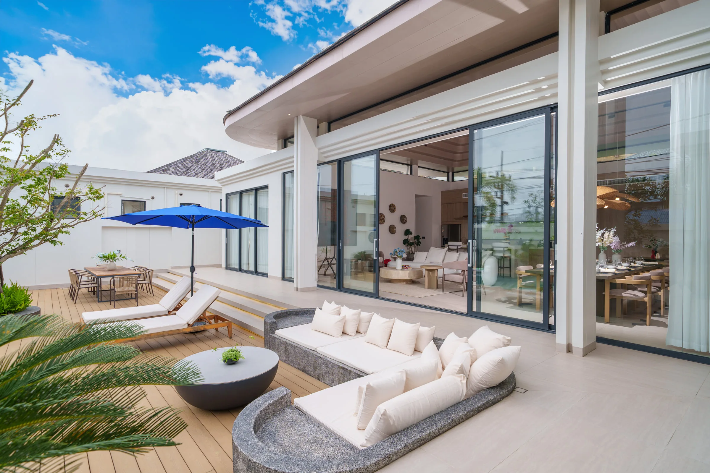 Covered terrace with a built-in sofa, low table and sun loungers beside the pool