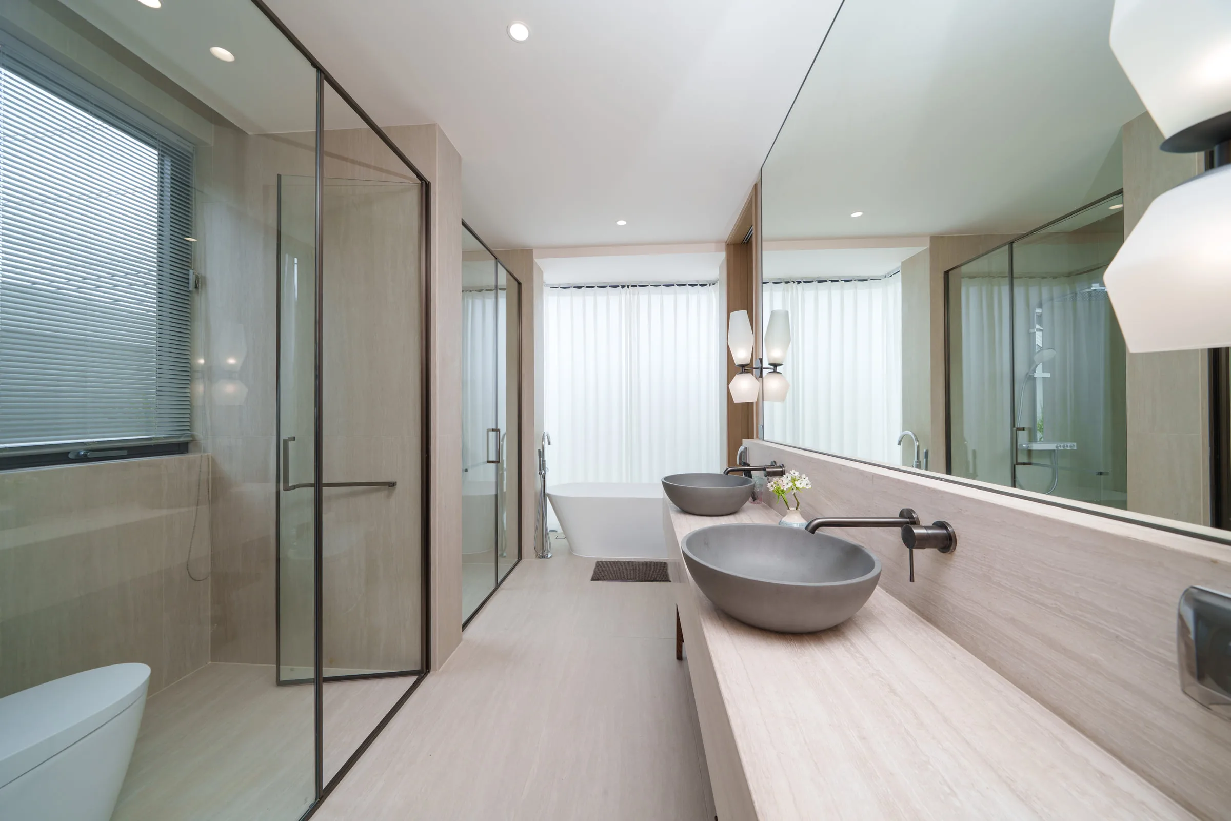 Bathroom with twin stone basins, a glazed shower and a bathtub at the far end