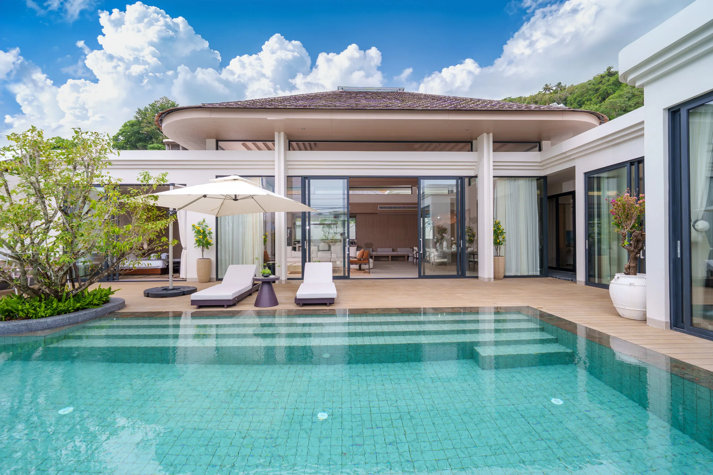 Swimming pool seen head-on, with sun loungers, parasol and the terrace behind