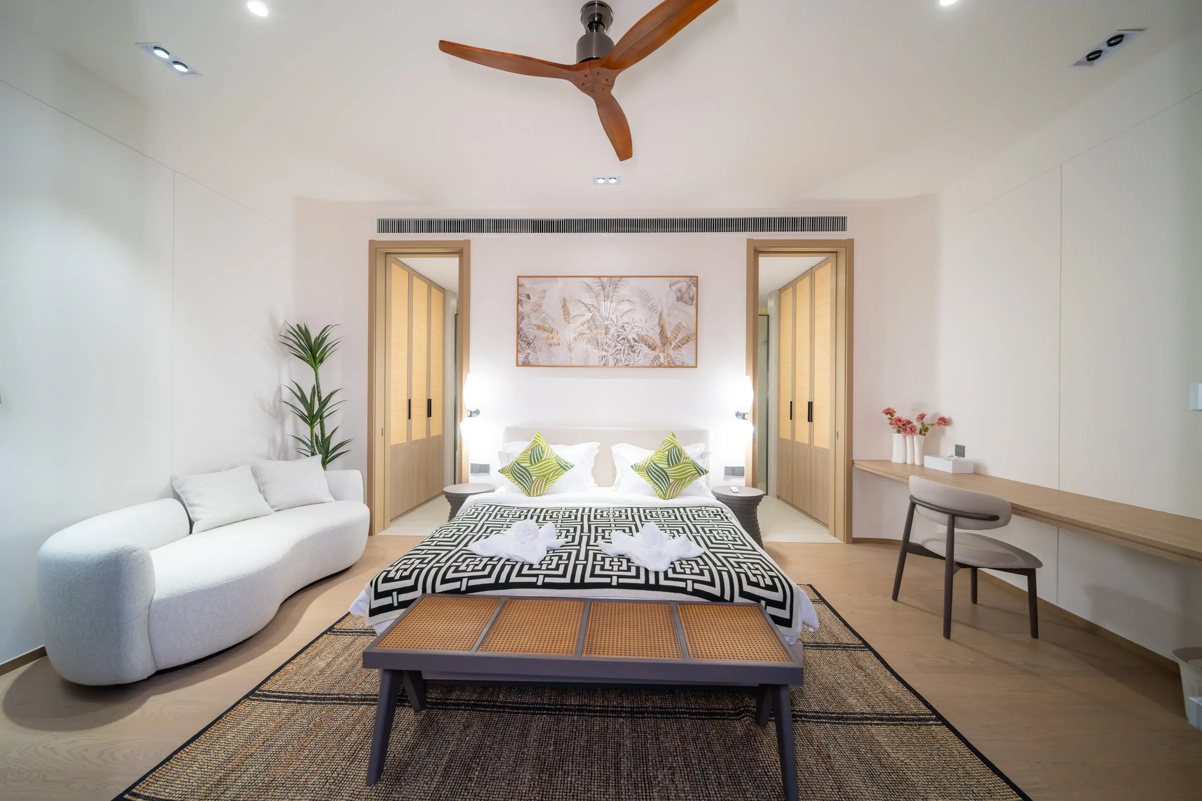 Bedroom with a double bed between two timber doors, a sofa and a desk