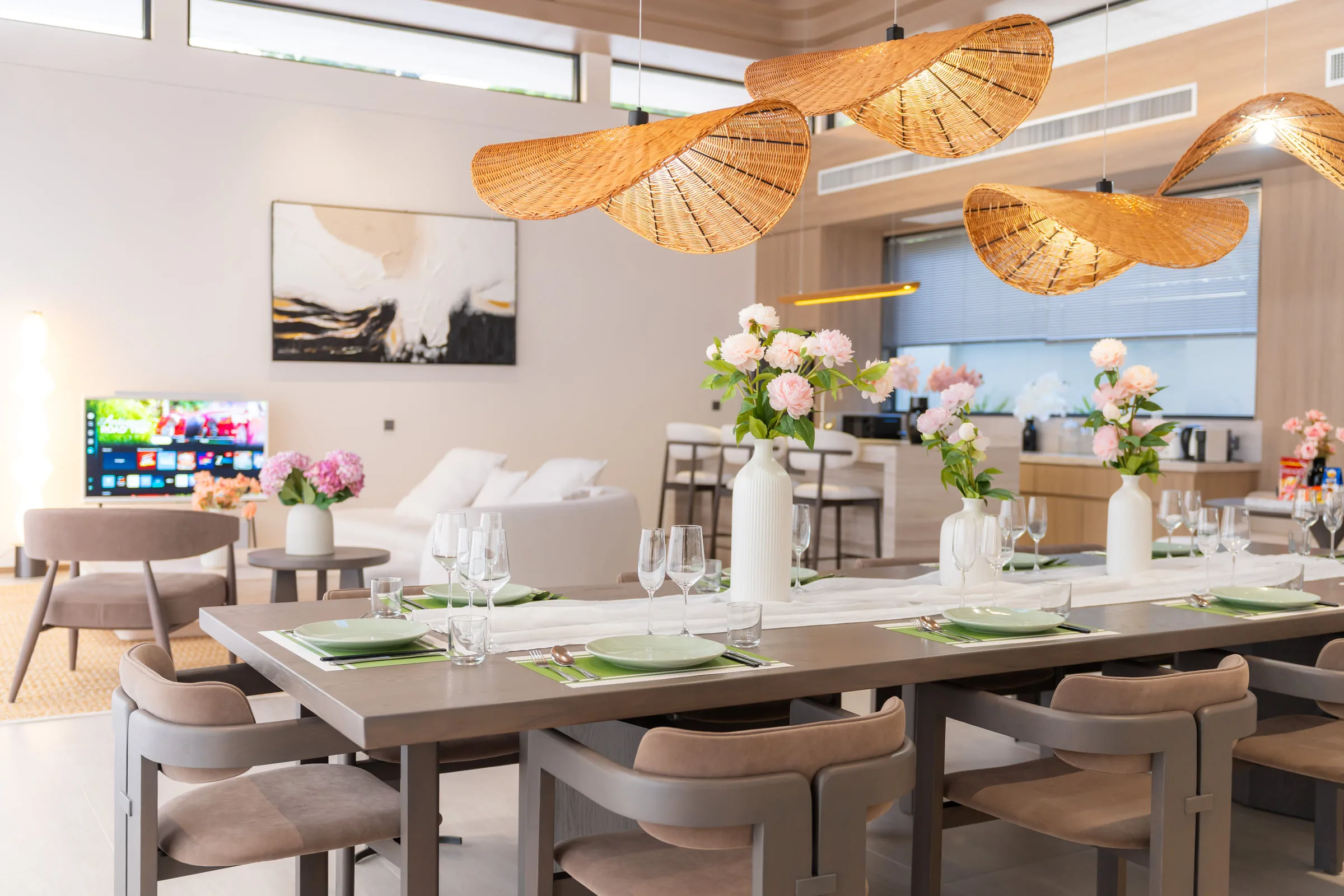 Dining table for ten laid for a meal, under woven pendant lights