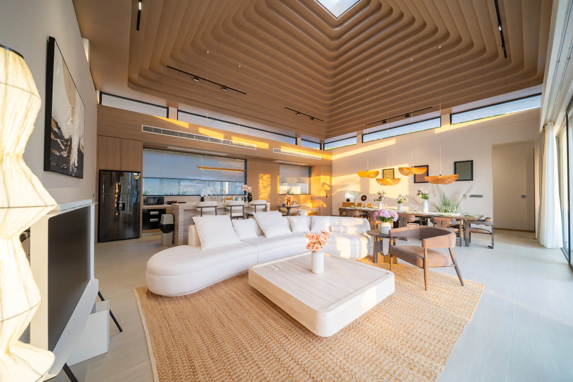 Living room with a curved sofa, low table and a high slatted timber ceiling