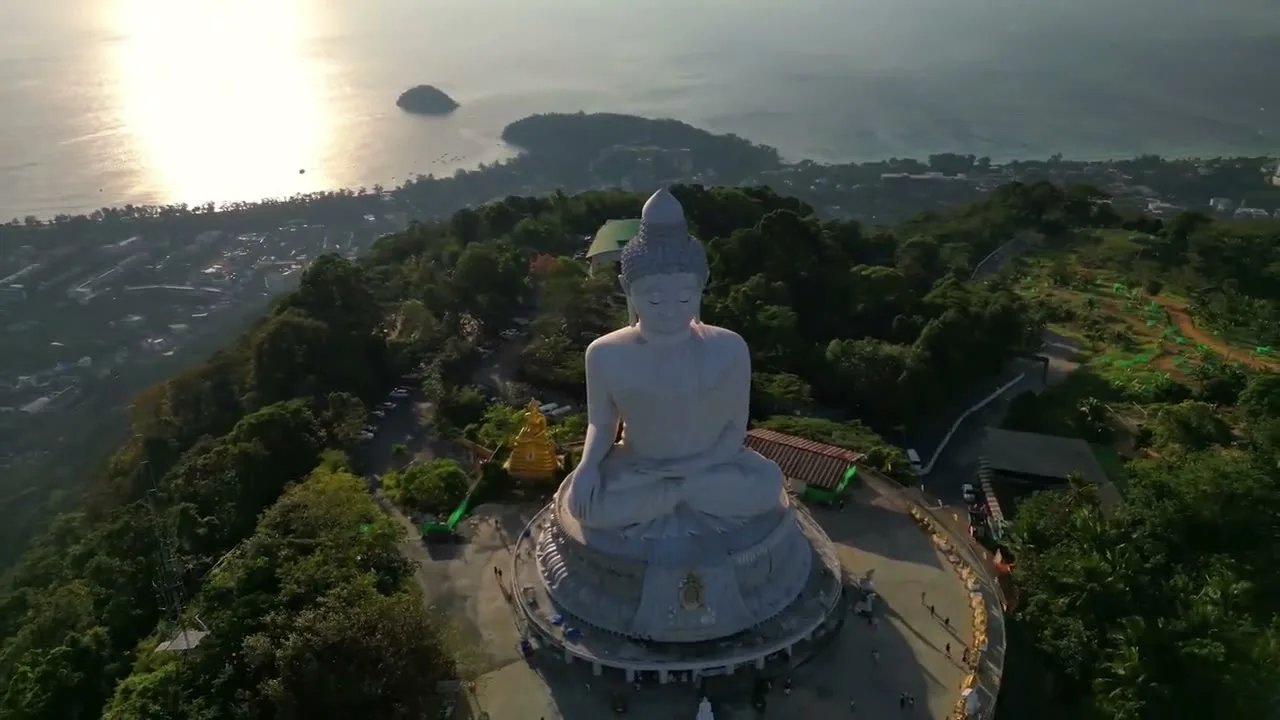 Aerial view of the Big Buddha of Phuket at golden hour, with Kata and Karon bays behind